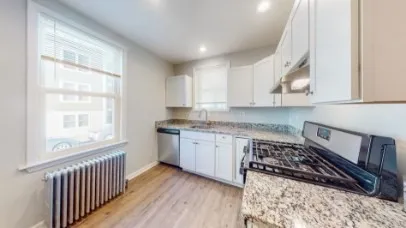 a kitchen with granite countertop a stove a sink and a refrigerator