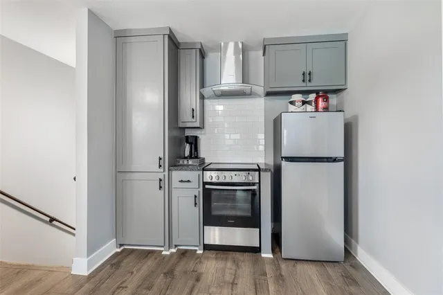 a kitchen with stainless steel appliances a refrigerator cabinets and wooden floor