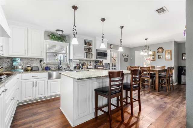 a kitchen with kitchen island granite countertop a table chairs sink and cabinets
