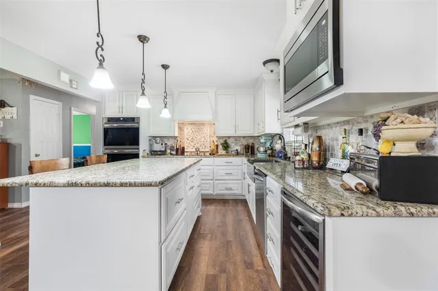 a kitchen with granite countertop a sink a counter top space stainless steel appliances and a chandelier