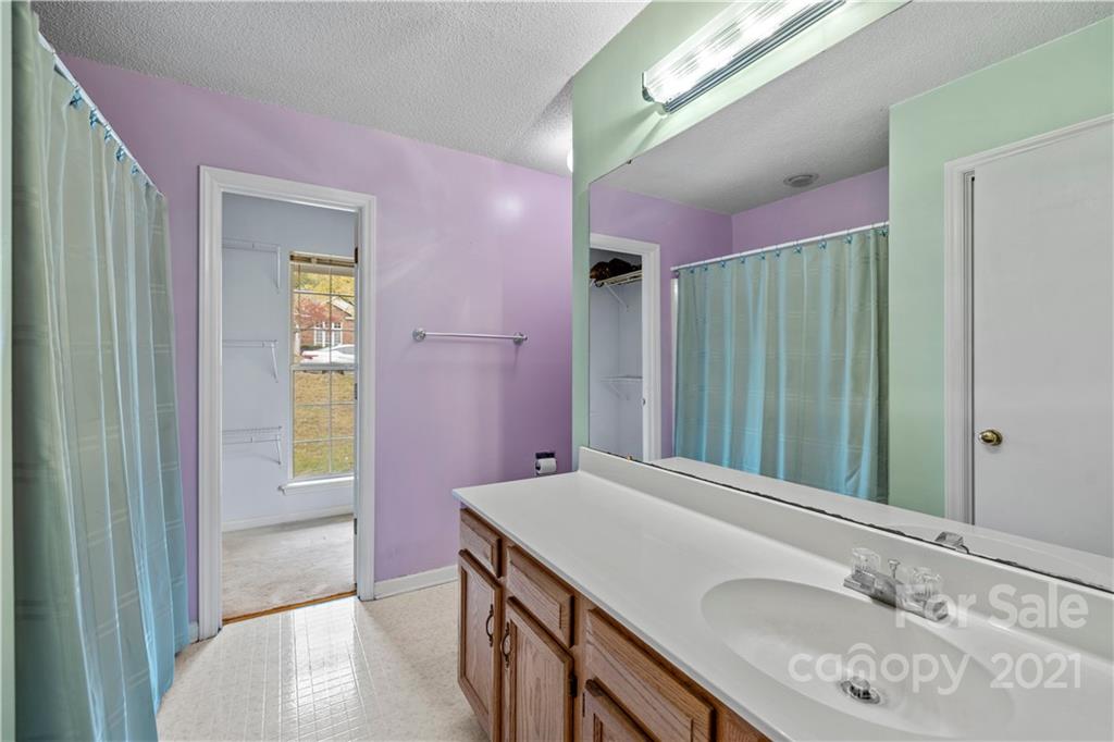 11232 Clayford Ridge Charlotte, NC 28215 - Photo 13 of 22 a bathroom with a granite countertop sink a mirror and a bathtub