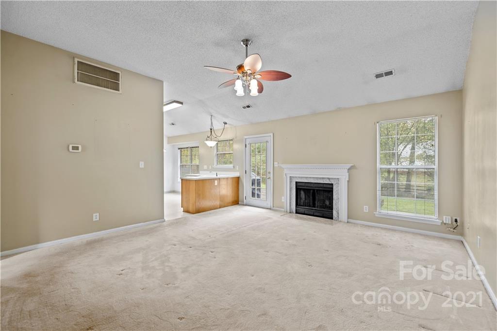 11232 Clayford Ridge Charlotte, NC 28215 - Photo 3 of 22 a view of a livingroom with a fireplace a ceiling fan and windows