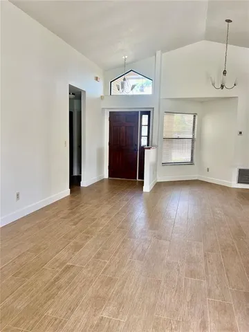 an empty room with wooden floor cabinet and windows