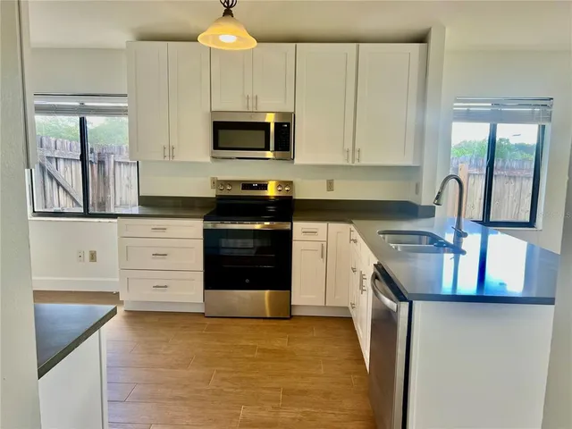 a kitchen with granite countertop a stove a sink and a microwave