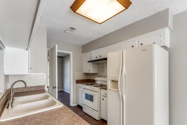 a kitchen with stainless steel appliances a refrigerator sink and white cabinets