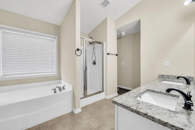 a bathroom with a granite countertop tub sink and mirror