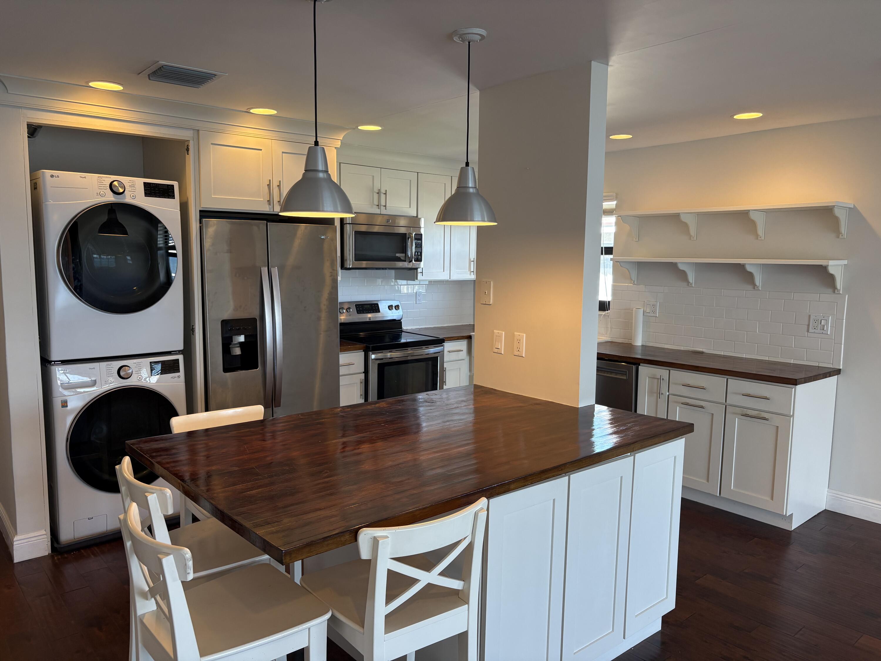 360 Wilma Circle, Unit 5 Riviera Beach, FL 33404 - Photo 7 of 16 a kitchen with stainless steel appliances a dining table chairs and a refrigerator
