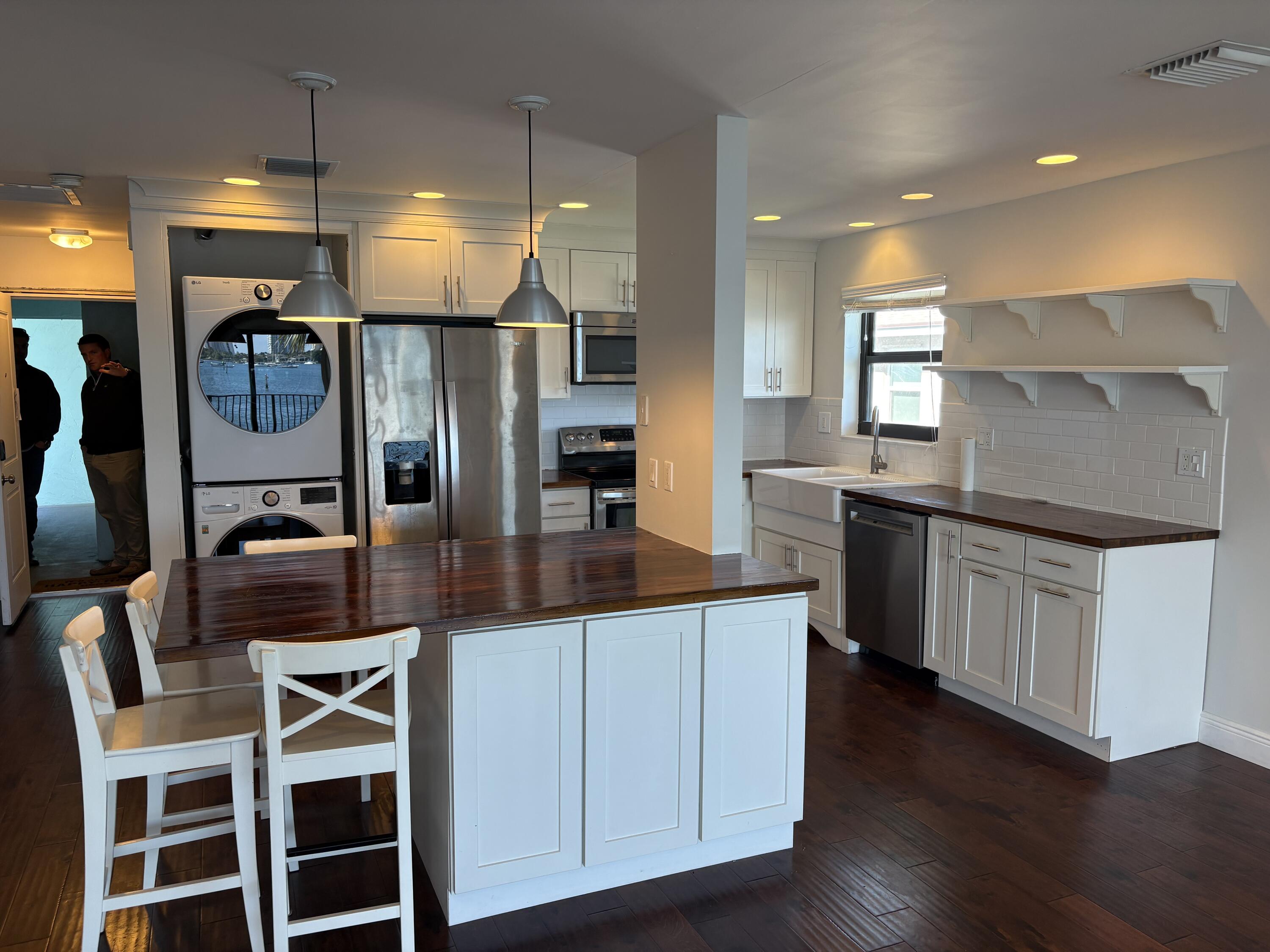 360 Wilma Circle, Unit 5 Riviera Beach, FL 33404 - Photo 8 of 16 a kitchen with stainless steel appliances kitchen island granite countertop a table and chairs