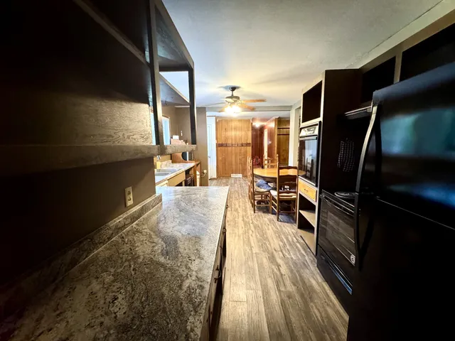 a living room with stainless steel appliances furniture a rug and a large window