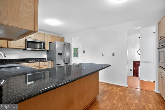 a kitchen with stainless steel appliances granite countertop a sink a stove and a refrigerator