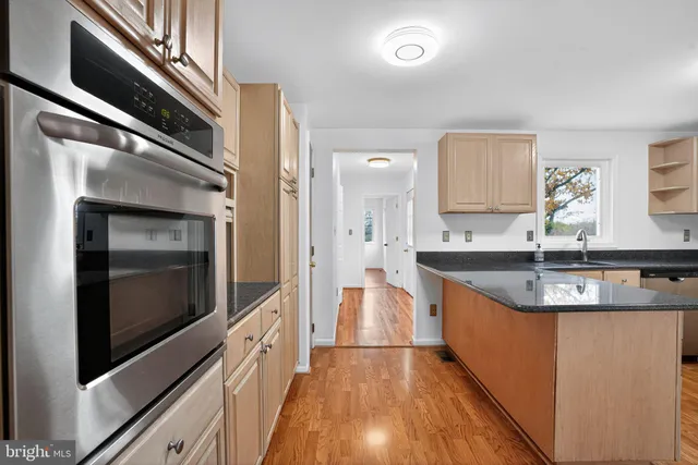 a large kitchen with granite countertop a sink and dishwasher a stove top oven with wooden floor