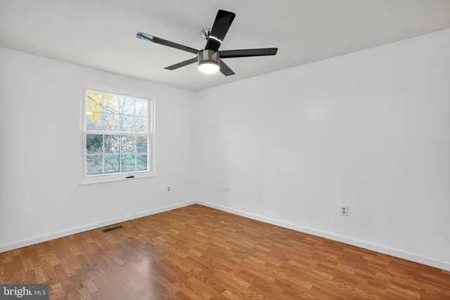 a view of a room with wooden floor and a ceiling fan