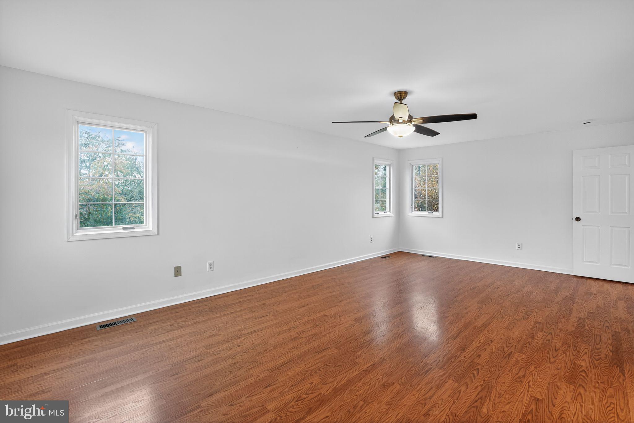 1513 Rainbow Drive Silver Spring, MD 20905 - Photo 28 of 58 an empty room with wooden floor chandelier fan and windows