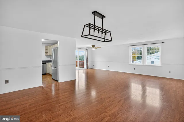 an empty room with wooden floor exposed radiator and windows
