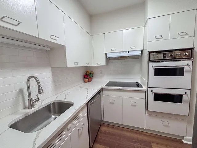 a kitchen with granite countertop a sink stainless steel appliances and cabinets