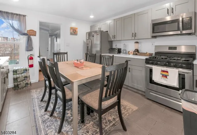 a kitchen with stainless steel appliances granite countertop a stove a sink dishwasher a dining table and chairs with wooden floor