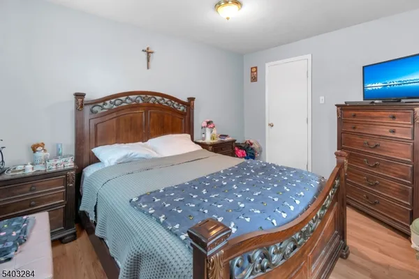 a bedroom with a bed and dresser with wooden floor