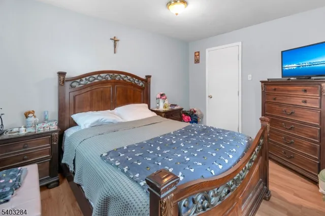 a bedroom with a bed and dresser with wooden floor