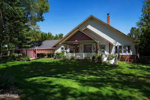 a front view of a house with a yard and a tree