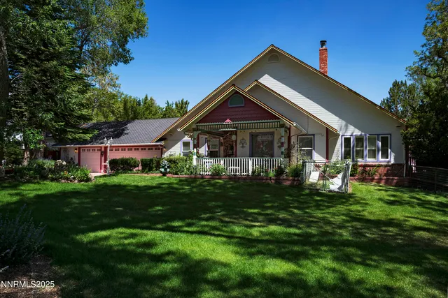 a front view of a house with a yard and a tree