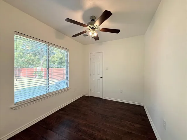 an empty room with wooden floor fan and windows