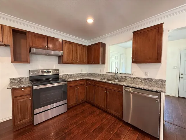 a kitchen with granite countertop wooden cabinets and a stove top oven