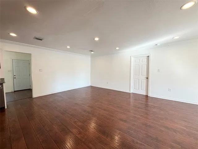 a view of an empty room with wooden floor and closet