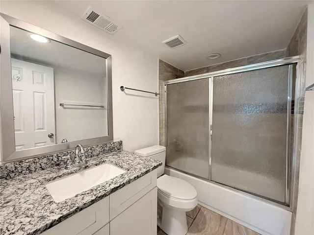 a bathroom with a granite countertop sink a toilet and shower