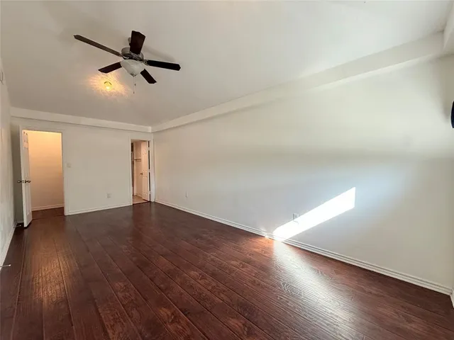 an empty room with wooden floor ceiling fan and windows