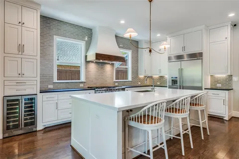 a kitchen with kitchen island a dining table chairs and white cabinets