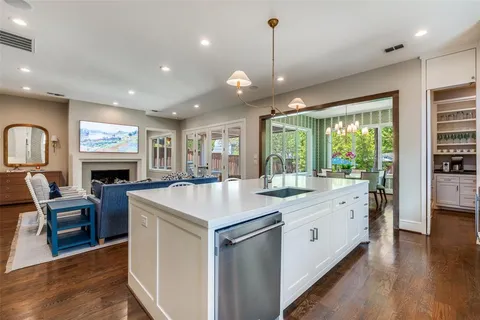 a large kitchen with kitchen island a stove a sink a dining table and chairs with wooden floor