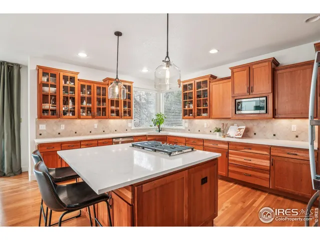 a kitchen that has a table chairs in it wooden floors and white cabinets