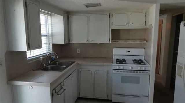 a kitchen with cabinets appliances a sink and a window