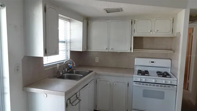 a kitchen with white cabinets sink and window