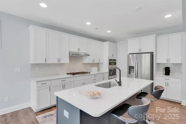 a kitchen with stainless steel appliances a sink a table and chairs