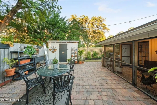 a view of a patio with a table and chairs under an umbrella with potted plants