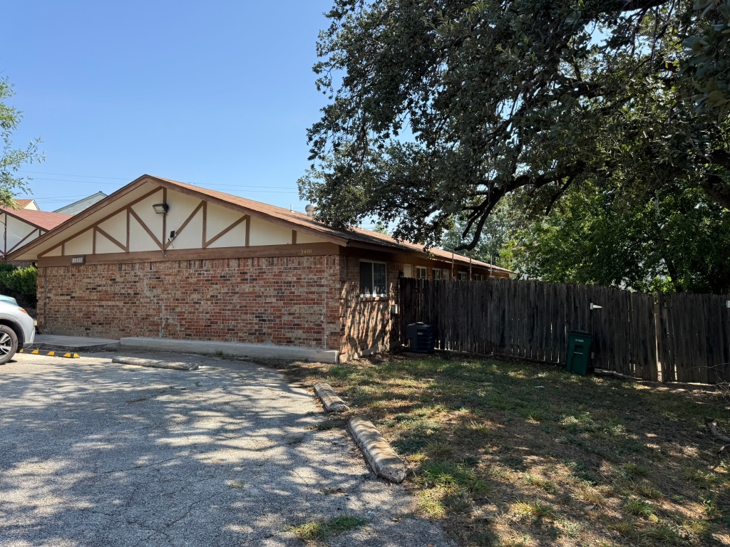a view of a house with a small yard and a large tree