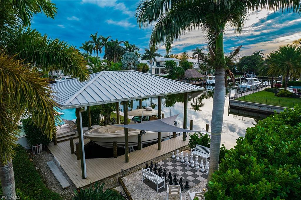 2290 Tarpon Road Naples, FL 34102 - Photo 13 of 50 a view of patio with table and chairs potted plants and palm tree