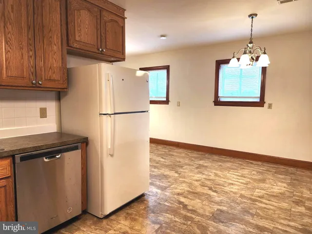 a kitchen with stainless steel appliances granite countertop a refrigerator a stove a sink dishwasher and wooden cabinets with wooden floor