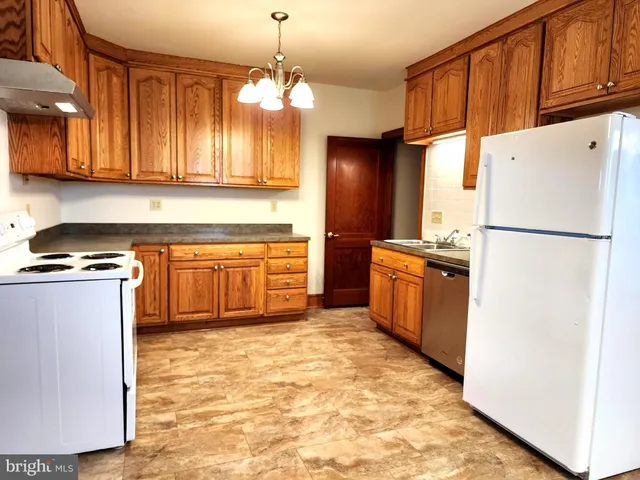 a kitchen with stainless steel appliances granite countertop a refrigerator a sink dishwasher a stove with wooden cabinets