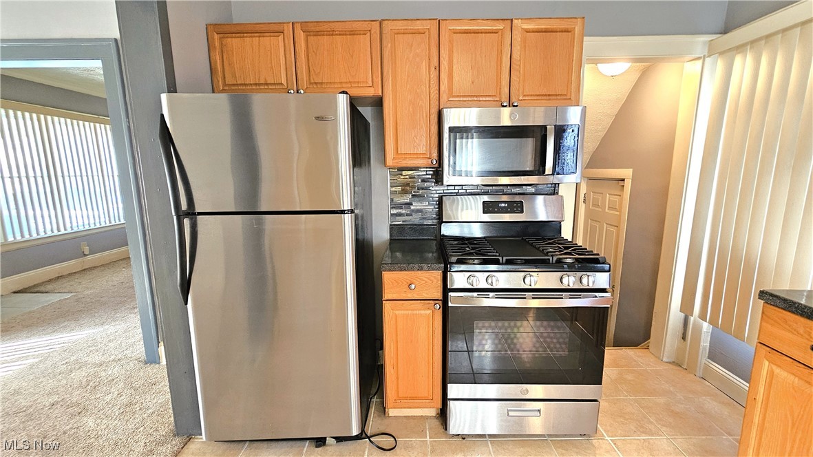 887 Rondel Road Cleveland, OH 44110 - Photo 16 of 34 Kitchen featuring tasteful backsplash, light colored carpet, and stainless steel appliances