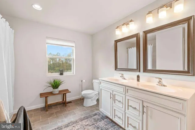 a spacious bathroom with a double vanity sink a toilet and a mirror