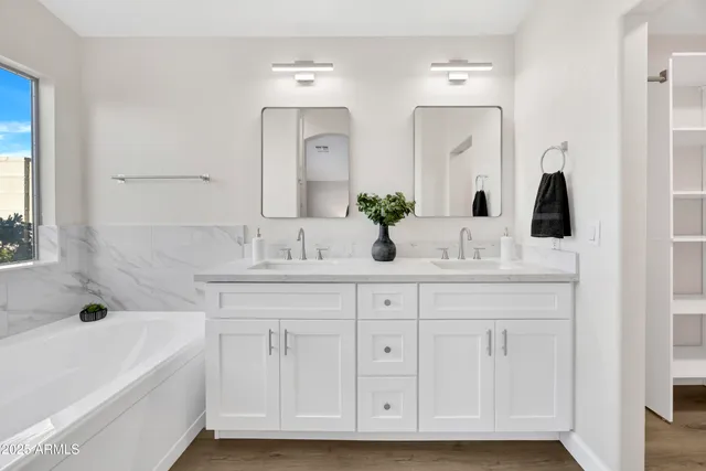 a bathroom with a double vanity sink mirror and bathtub