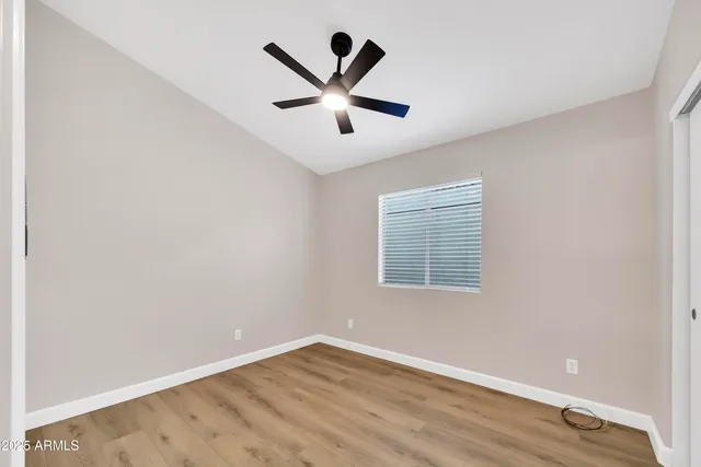 an empty room with ceiling fan and window
