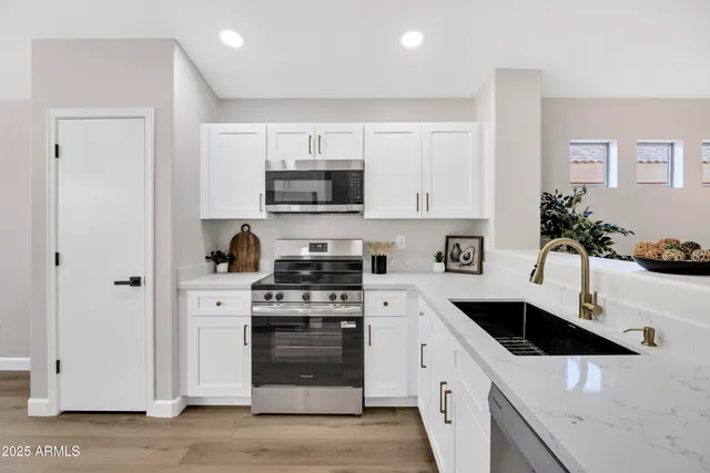 a kitchen with stainless steel appliances white cabinets a sink a stove and a refrigerator