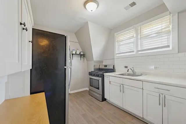 a kitchen with a sink cabinets stainless steel appliances and a window