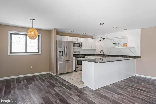 a kitchen with stainless steel appliances granite countertop a sink a stove a refrigerator and cabinets