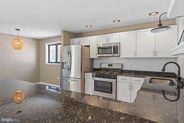 a hall with kitchen island granite countertop a sink and a large window