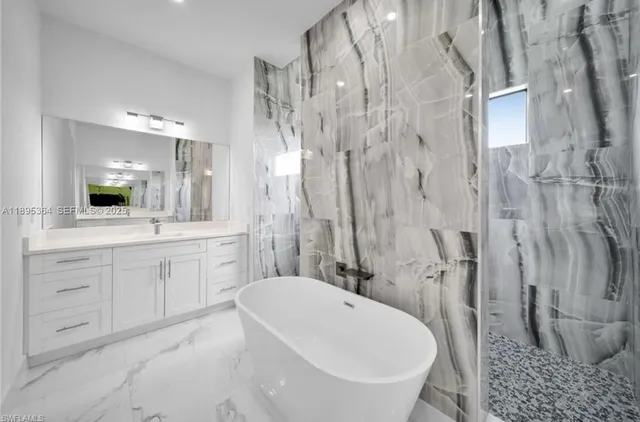a white bath tub sitting next to a white sink and vanity