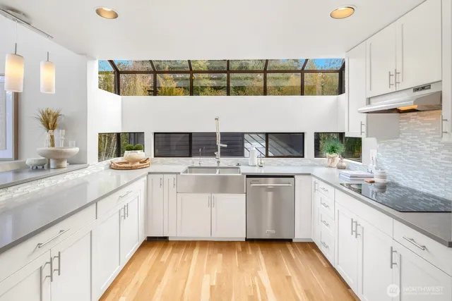 a kitchen with a sink dishwasher a stove and white cabinets with wooden floor